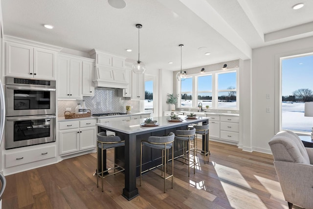 4181 Arbor Dr, Woodbury, MN 55129 - kitchen featuring tasteful backsplash, double oven, a breakfast bar area, white cabinetry, and gas stovetop