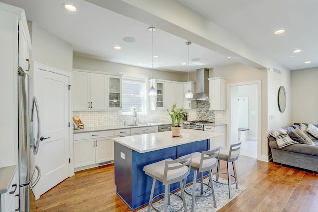 kitchen featuring stainless steel appliances, tasteful backsplash, visible vents, and wall chimney exhaust hood
