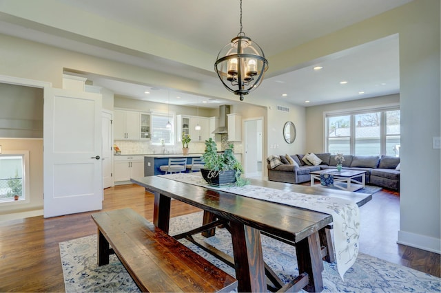 dining space featuring an inviting chandelier, wood finished floors, baseboards, and recessed lighting