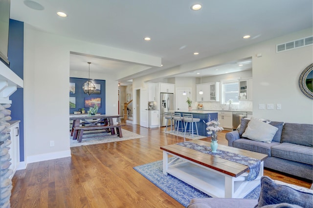living room featuring a notable chandelier, recessed lighting, baseboards, visible vents, and light wood-style floors