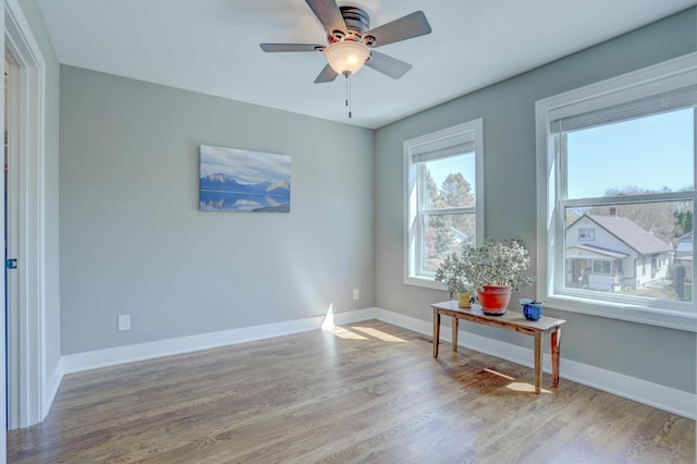 unfurnished room featuring wood finished floors, baseboards, and ceiling fan