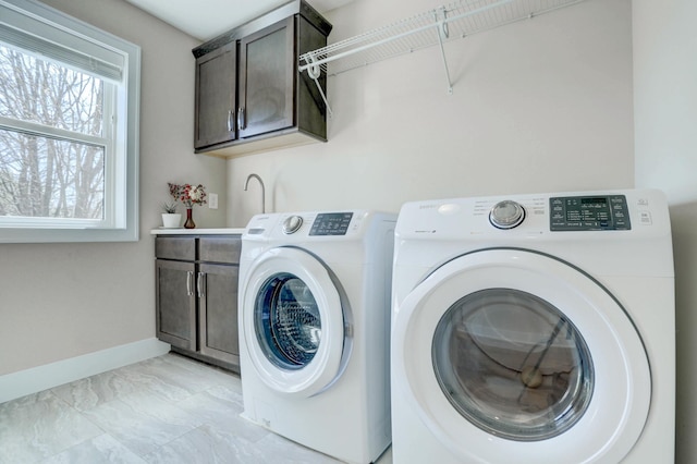 washroom with cabinet space, washer and clothes dryer, baseboards, and marble finish floor