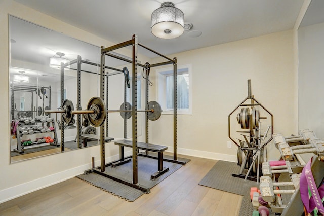 exercise room with baseboards and wood finished floors