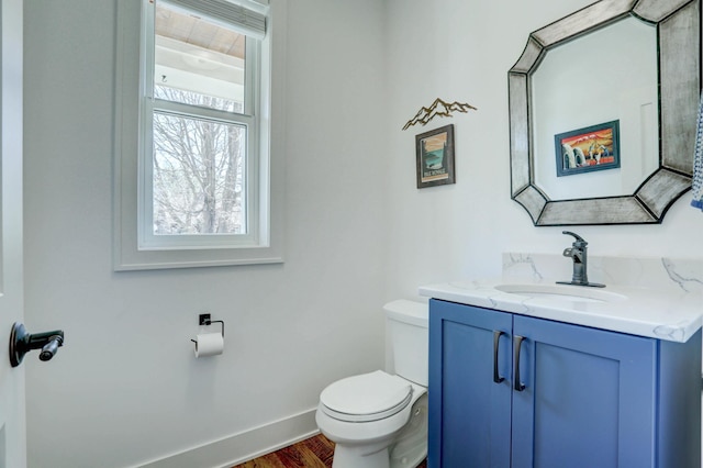 bathroom with toilet, baseboards, vanity, and wood finished floors