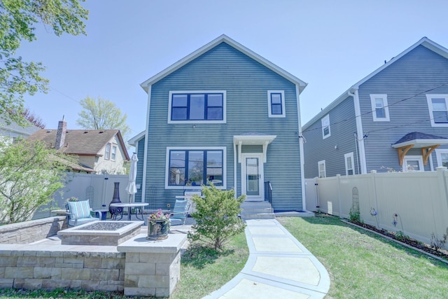 view of front of property featuring a front yard, a fire pit, and a fenced backyard