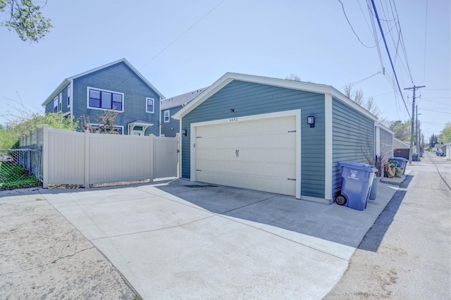 garage featuring driveway and fence