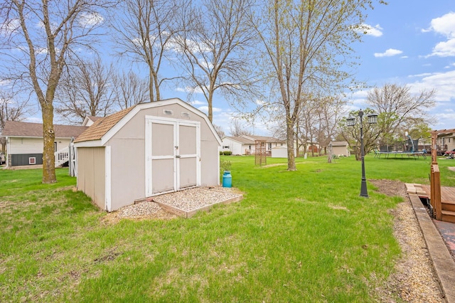 view of yard with an outbuilding, a trampoline, a storage shed, and a residential view