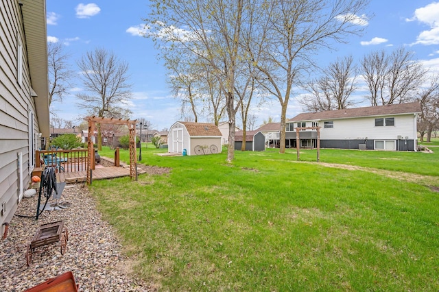 view of yard featuring an outdoor structure, a pergola, a wooden deck, and a shed