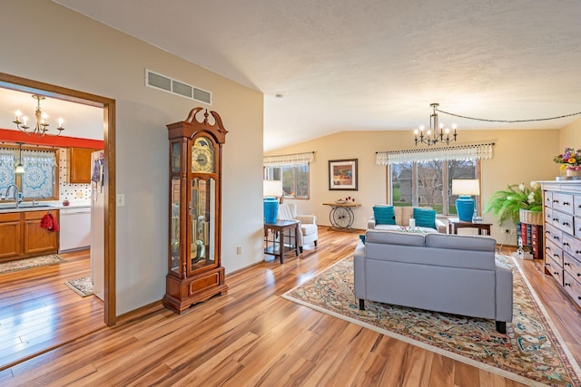 living room with a chandelier, visible vents, and light wood-style floors