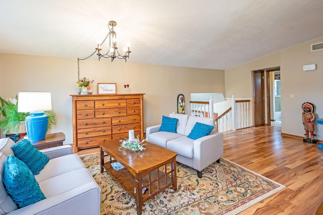 living room featuring baseboards, visible vents, wood finished floors, and a chandelier