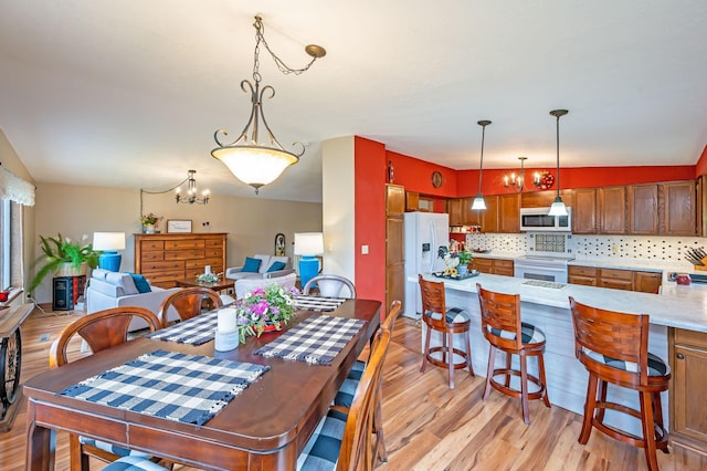 dining room with light wood-type flooring and a notable chandelier