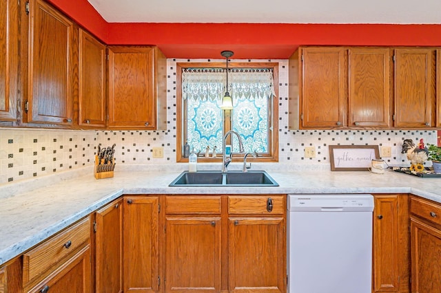 kitchen with brown cabinetry, a sink, dishwasher, and light countertops