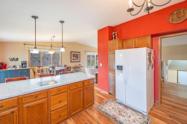 kitchen featuring light wood-type flooring, light countertops, vaulted ceiling, and white fridge with ice dispenser