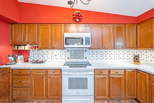 kitchen featuring decorative backsplash, brown cabinetry, light stone countertops, lofted ceiling, and white electric range oven