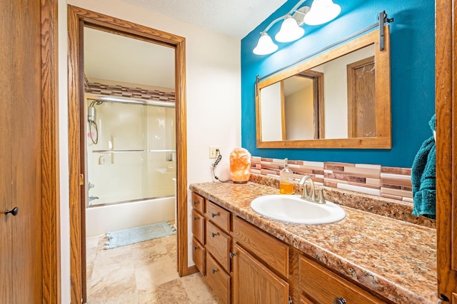 bathroom featuring vanity, combined bath / shower with glass door, and a textured ceiling