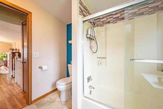 bathroom featuring shower / bath combination with glass door, baseboards, and toilet