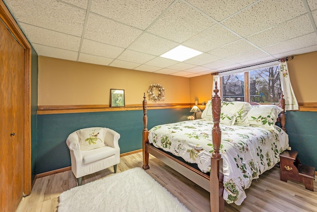 bedroom featuring wood finished floors, baseboards, and a drop ceiling