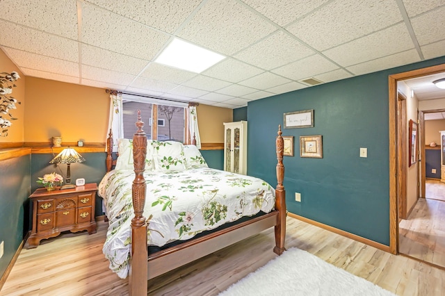 bedroom featuring visible vents, baseboards, a paneled ceiling, and wood finished floors