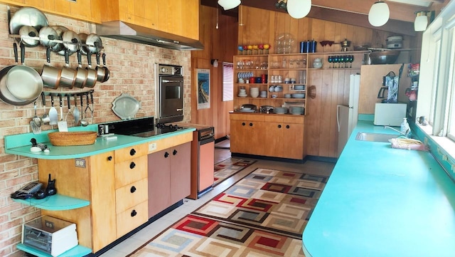 kitchen featuring black electric cooktop, light countertops, a sink, under cabinet range hood, and oven