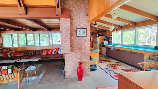 interior space featuring a ceiling fan, vaulted ceiling with beams, and light floors
