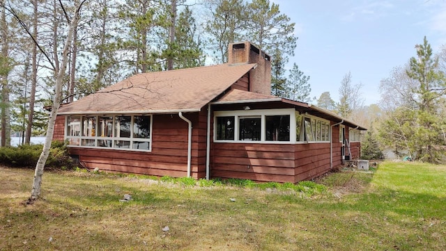 view of side of home with a yard and a chimney