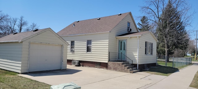 exterior space featuring fence, driveway, a garage, an outbuilding, and cooling unit