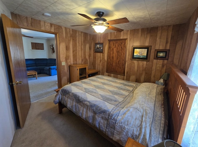 carpeted bedroom featuring wood walls and ceiling fan