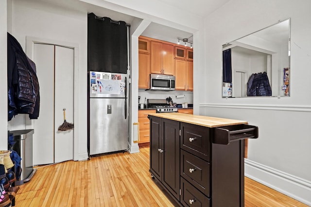 1204 Harmon Pl Unit 18, Minneapolis, MN 55403 - kitchen featuring stainless steel appliances, butcher block counters, light wood finished floors, glass insert cabinets, and a center island