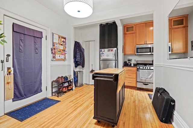 1204 Harmon Pl Unit 18, Minneapolis, MN 55403 - kitchen featuring appliances with stainless steel finishes, butcher block countertops, light wood-style floors, and glass insert cabinets