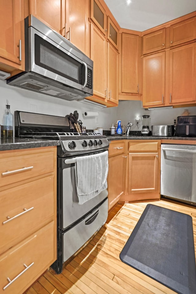 1204 Harmon Pl Unit 18, Minneapolis, MN 55403 - kitchen with stainless steel appliances, wood-type flooring, glass insert cabinets, and dark stone counters