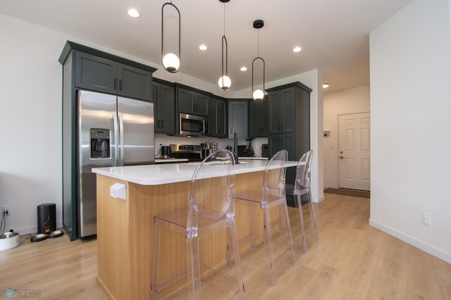4964 Big Goose Ln S, Fargo, ND 58104 - kitchen with stainless steel appliances, light wood-style flooring, a breakfast bar area, light countertops, and recessed lighting