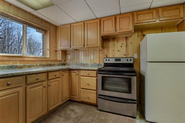 kitchen featuring freestanding refrigerator, wood walls, light countertops, stainless steel electric stove, and carpet flooring