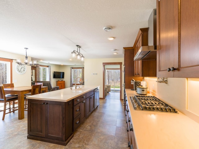 kitchen with a sink, wall chimney exhaust hood, stainless steel appliances, and plenty of natural light
