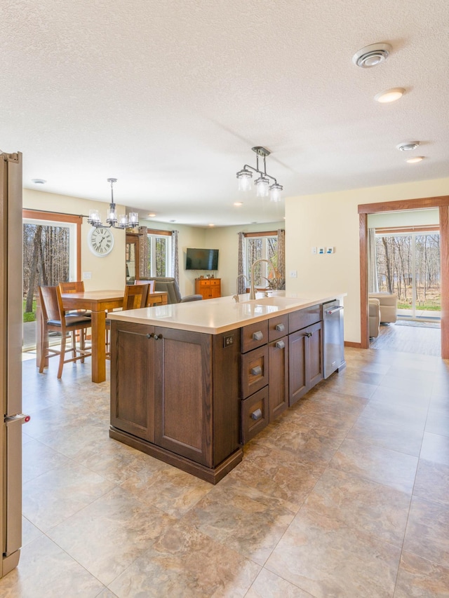 kitchen with a chandelier, stainless steel appliances, a textured ceiling, a sink, and dark brown cabinets