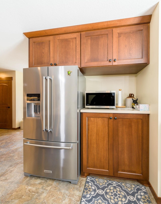 kitchen featuring appliances with stainless steel finishes, brown cabinets, and light countertops