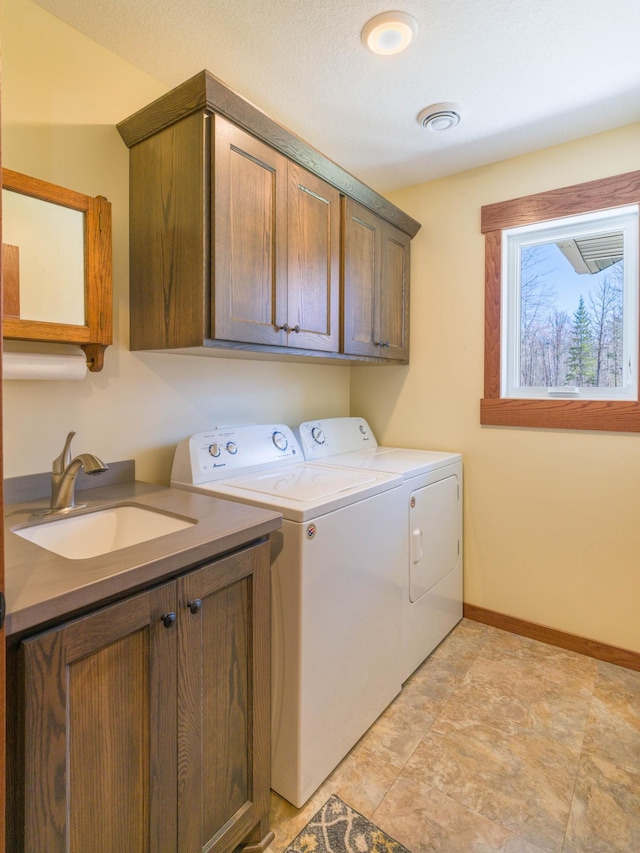 clothes washing area with cabinet space, separate washer and dryer, and baseboards