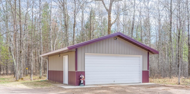 detached garage with a view of trees