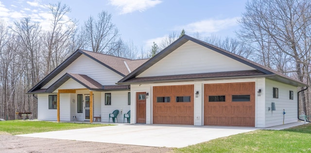 view of front of house featuring driveway, roof with shingles, a garage, covered porch, and a front lawn