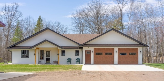 view of front of property with an attached garage, driveway, roof with shingles, and a front yard