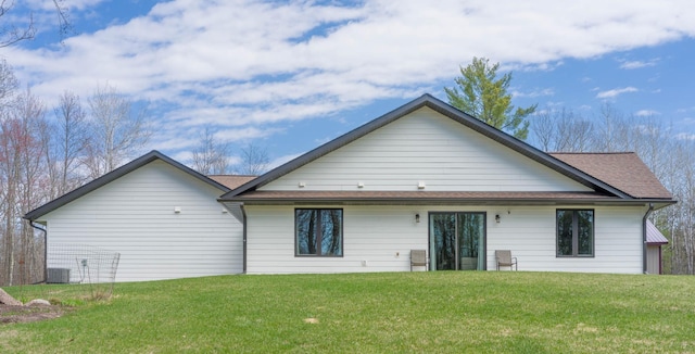 back of property with a yard, central AC unit, and a shingled roof