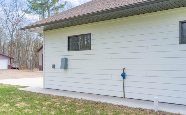 view of property exterior with roof with shingles, driveway, an outbuilding, and a detached garage