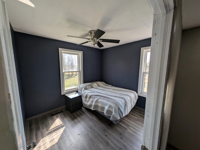 bedroom with wood finished floors, baseboards, and ceiling fan
