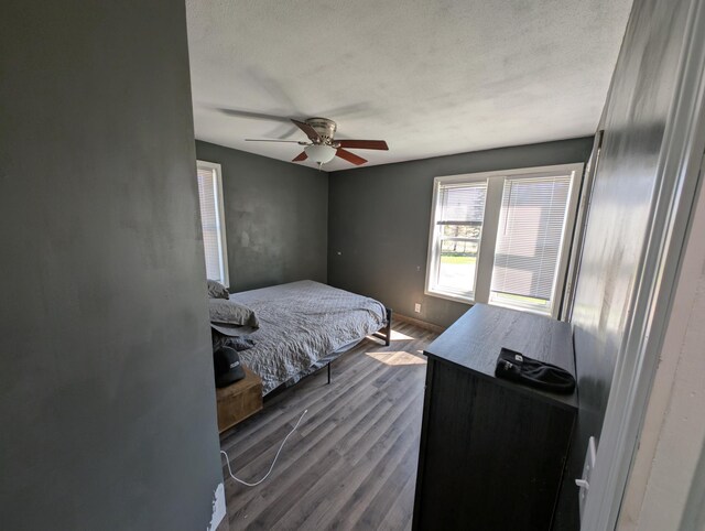 bedroom with dark wood-type flooring, ceiling fan, and a textured ceiling
