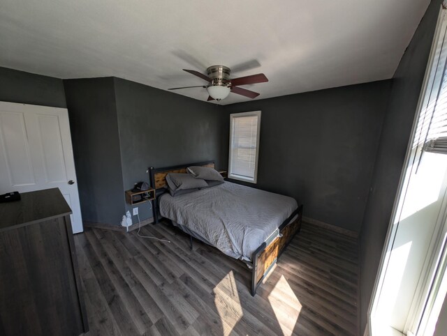 bedroom featuring multiple windows, baseboards, dark wood-style flooring, and ceiling fan