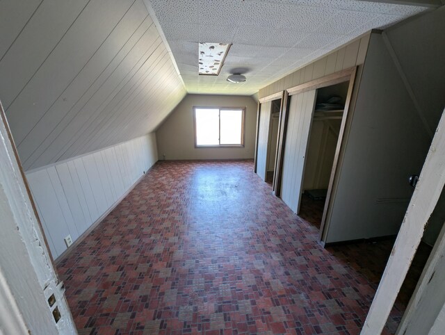 bonus room with wooden walls and vaulted ceiling