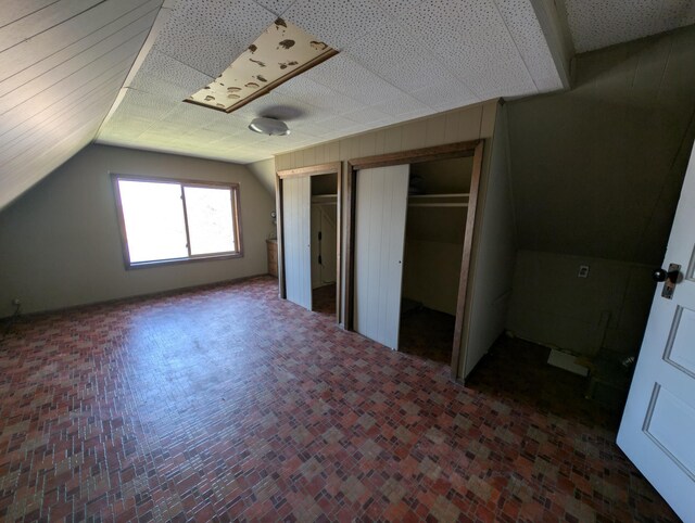 unfurnished bedroom with multiple closets and vaulted ceiling