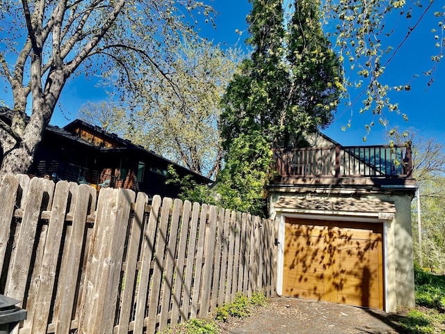 view of property exterior with fence, a balcony, and driveway