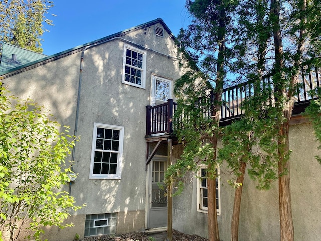 back of property featuring a balcony and stucco siding