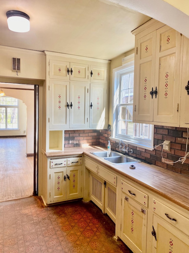 kitchen featuring visible vents, a sink, light countertops, and tasteful backsplash