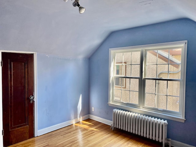 bonus room with baseboards, vaulted ceiling, radiator heating unit, and wood finished floors